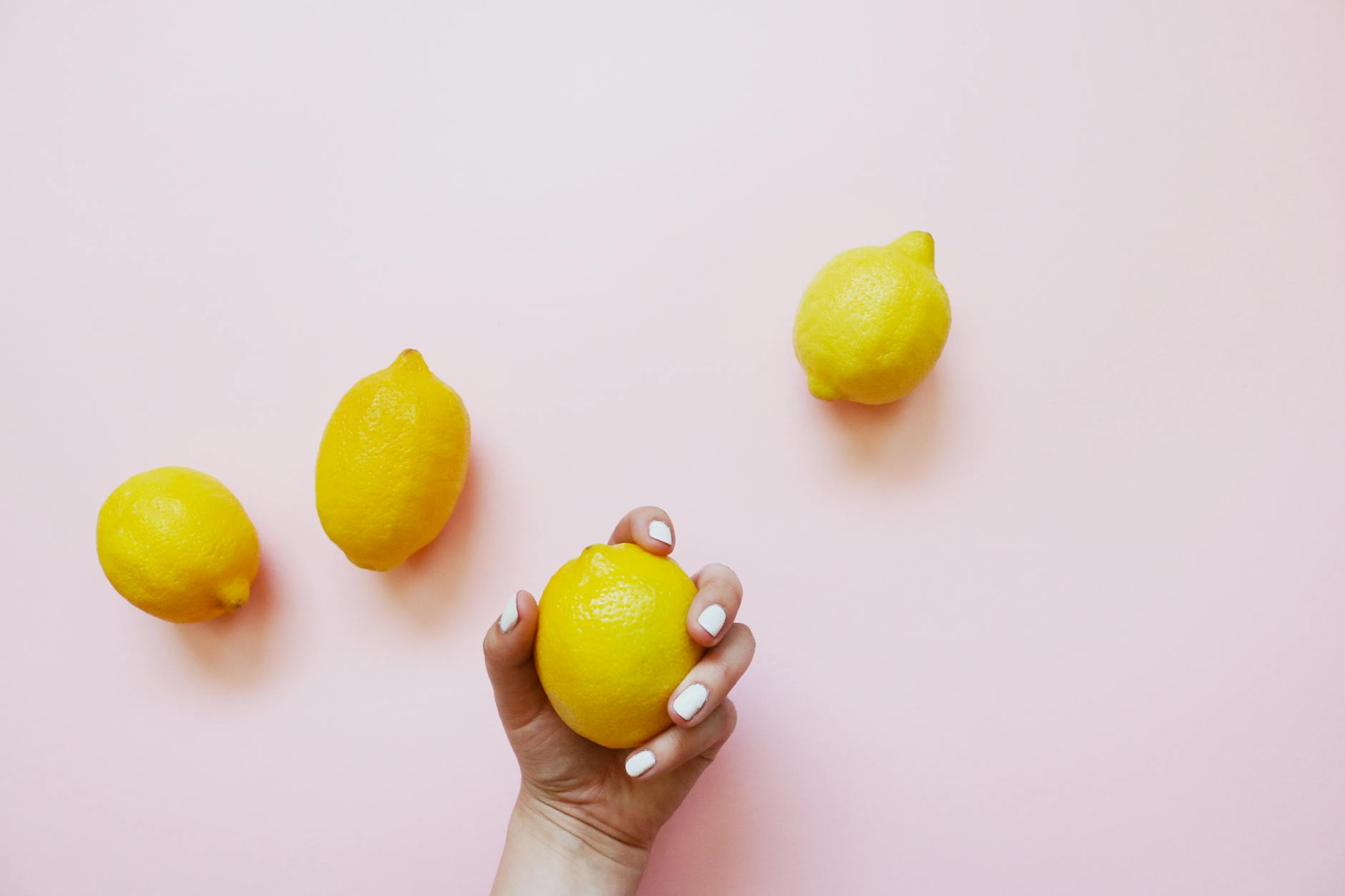 Fresh yellow lemons arranged on soft pink background, symbolizing gentle sensory grounding