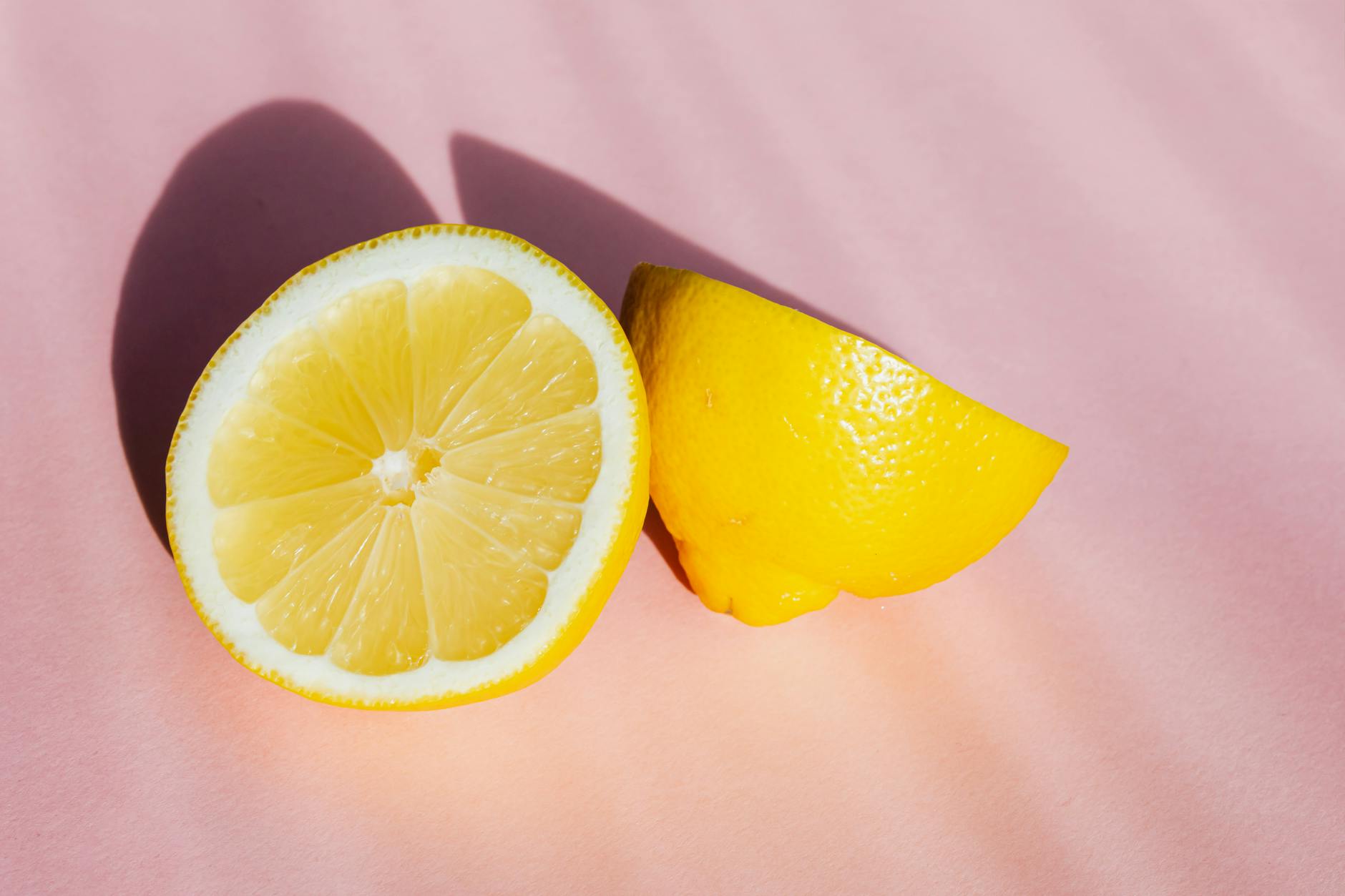 Fresh lemon halves on a pink background in sunlight, symbolizing brightness and reconnection