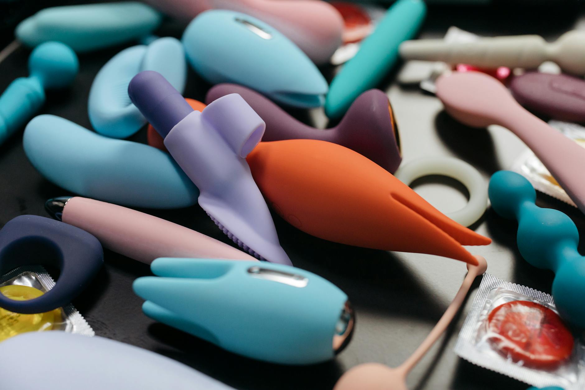 A woman with eyeglasses holding two colorful vibrators, showing diverse options for pleasure