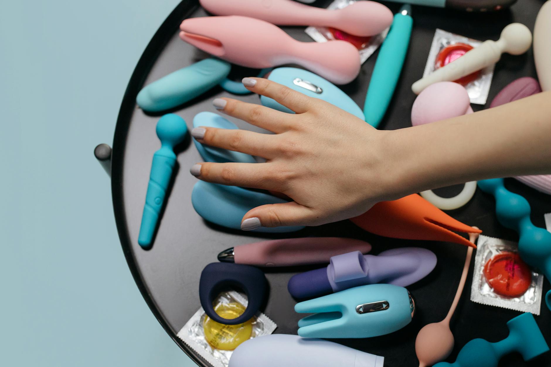 A woman holding a pink vibrator with art books in the background, representing intimate self-exploration and pleasure during hormonal changes.
