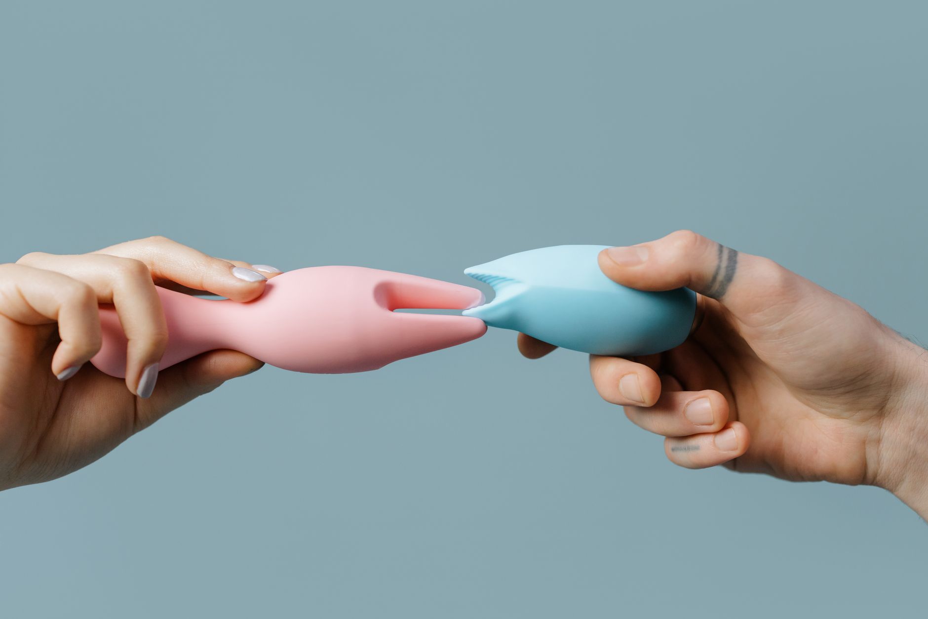 Hands holding pastel-colored silicone sex toys for couples and solo play