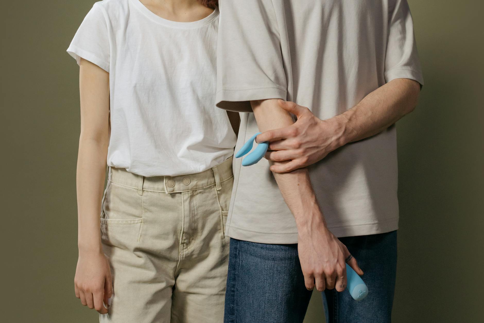 A young couple standing together indoors, exploring pleasure with a vibrator as part of their intimate connection.