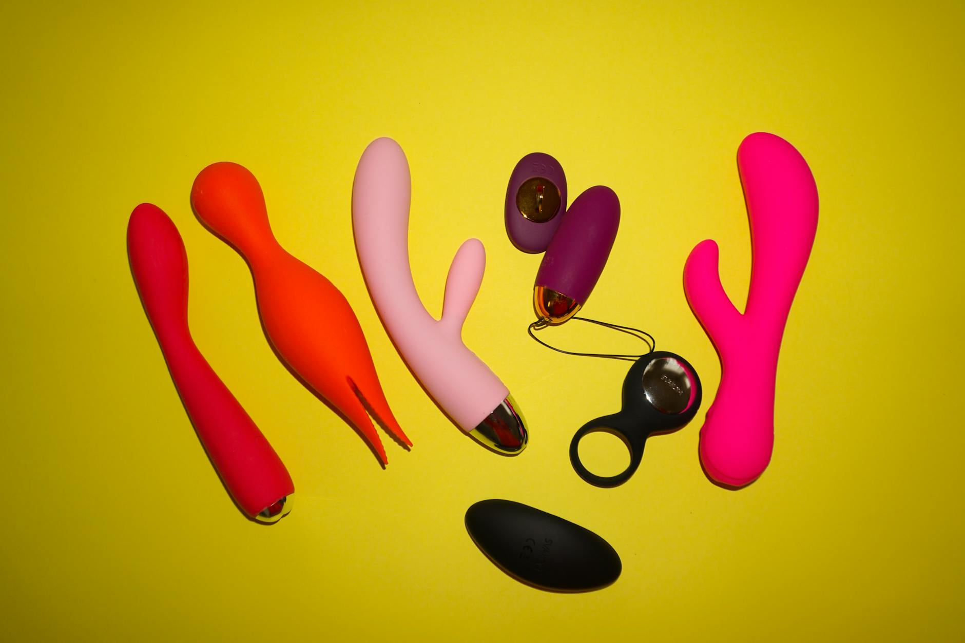 Hand holding a silicone clitoral vibrator against a purple background
