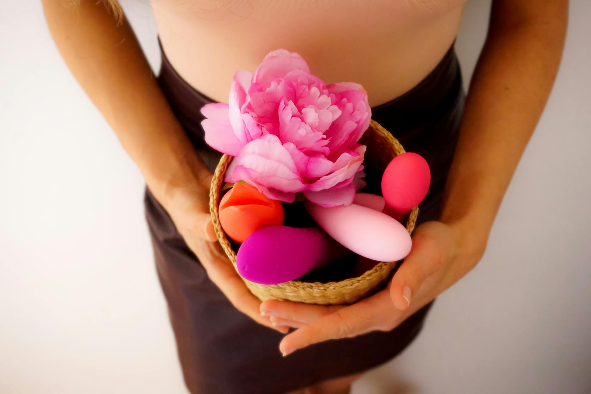 A basket containing colorful vibrators and fresh flowers, representing pleasure and self-care.
